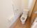トイレには洋式便器が設置されている。壁側には手すり、ペーパーフォルダー、呼び出しボタンが取り付けられている。
