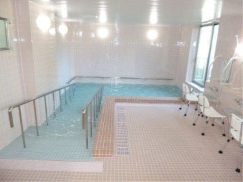 白を基調とした明るい清潔感のある大浴場である。浴槽までは安全に利用できるように、手すりの付いたスロープが完備されている。