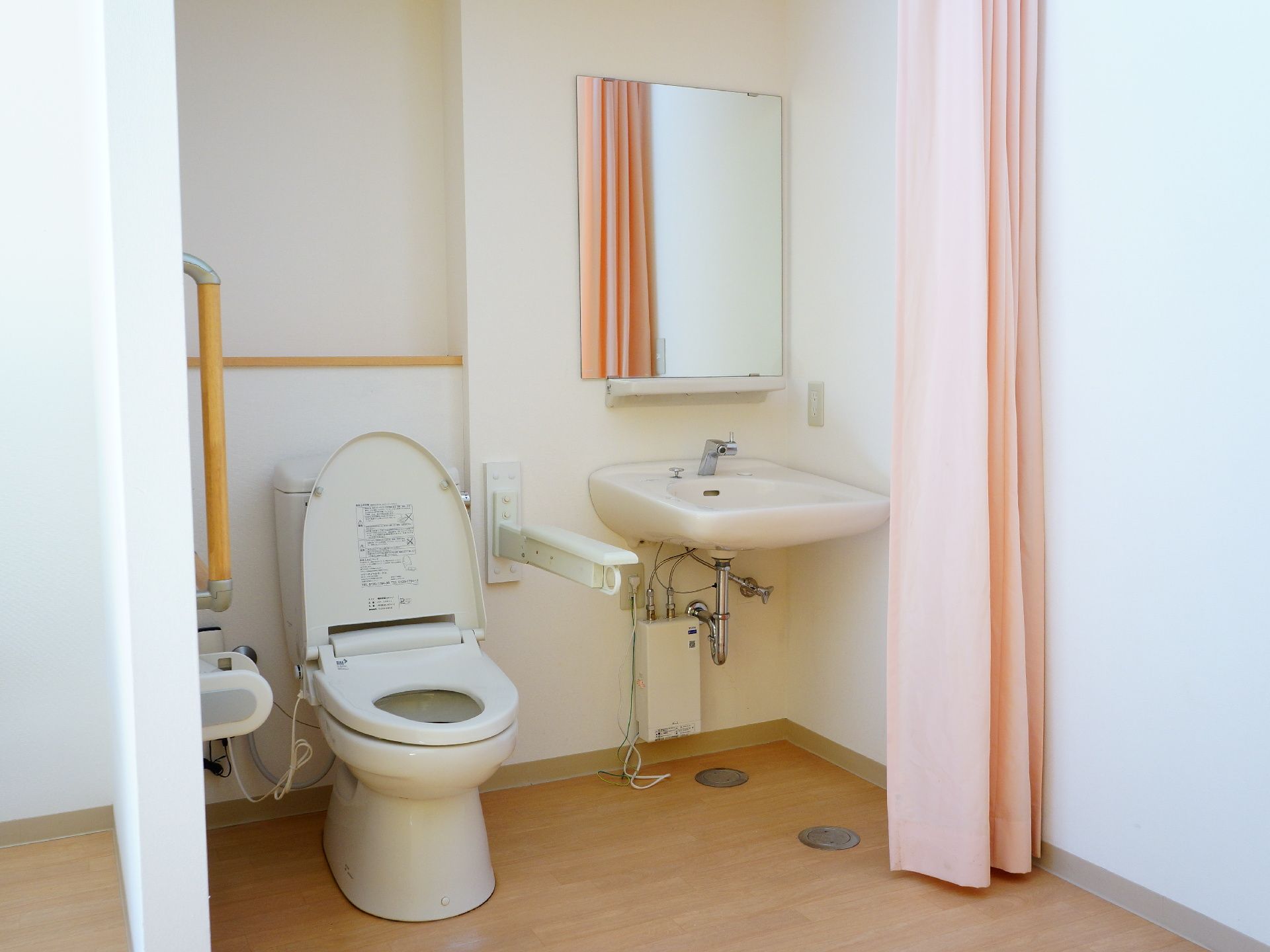トイレと洗面台はすぐそばにあり、ほとんど離れていない。ピンクのカーテンが用意されていて、落ち着いてトイレを使用できる。