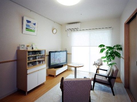 居室はフローリングの床になっており、カーペットが敷いてある。テレビやソファー椅子、水屋が備え付けてある。