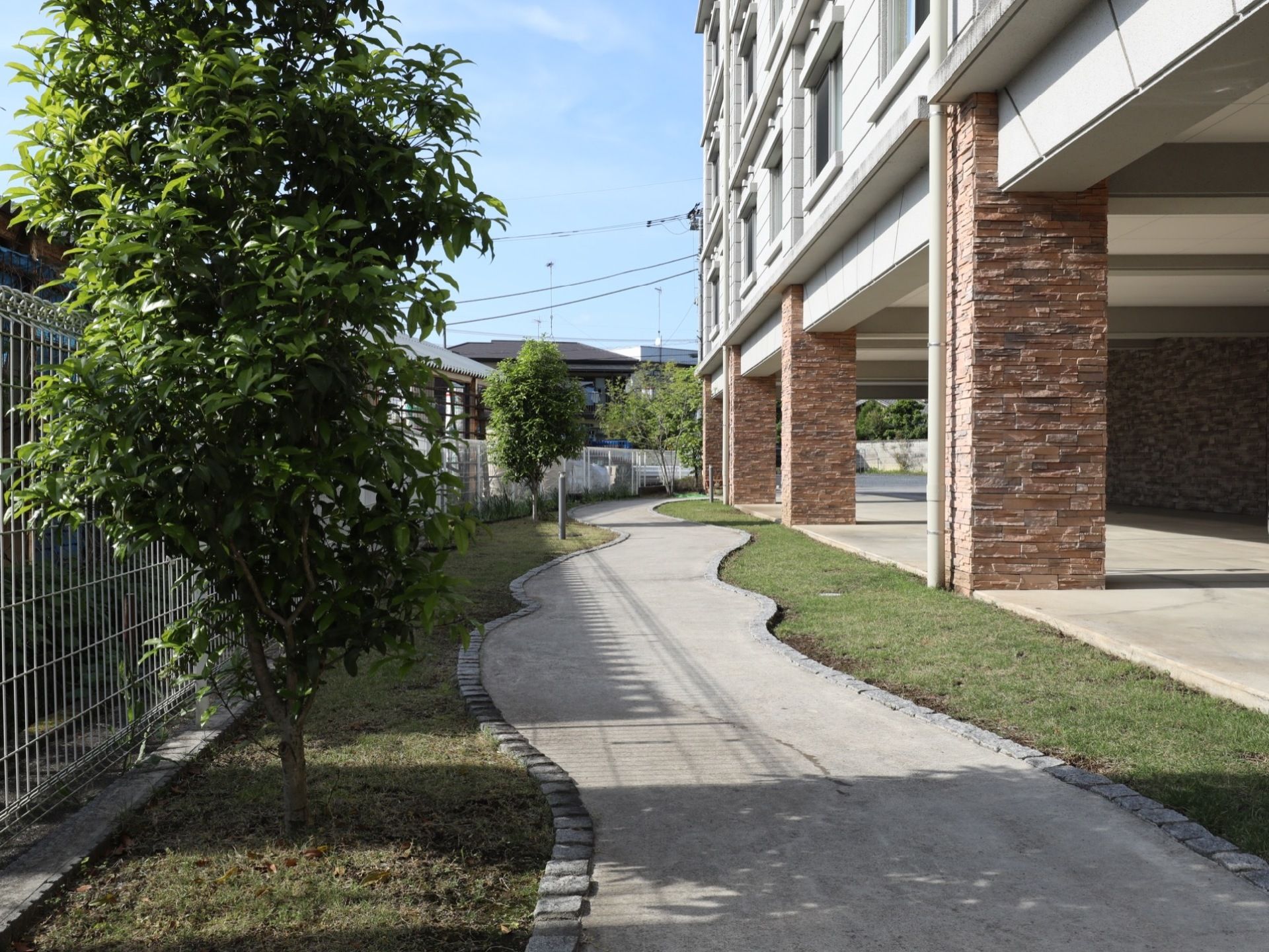 隣地との境は、フェンスで区切られている。敷地内の建物周辺にはが樹木や芝生が植えられ、その中に小道が作られている。