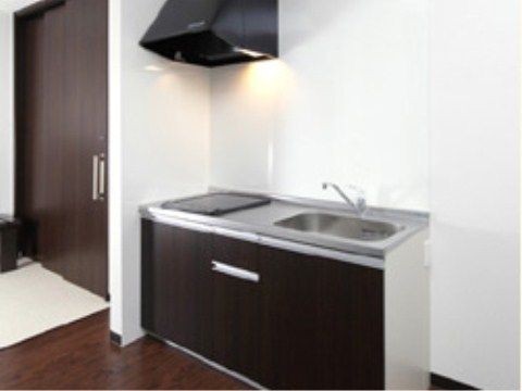 フローリングの部屋に設置されたIHキッチンと流しと換気扇