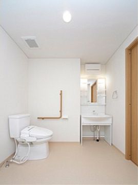 バリアフリー構造で広々としている。壁には手すりが取り付けられている。同じ空間に洗面台が設置されている。
