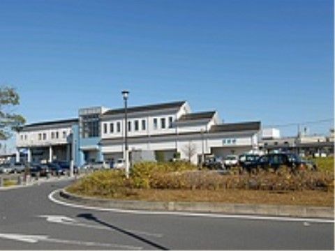 三角屋根に白い外壁の駅舎である。駅前は広いロータリーになっていてタクシーが停まっている。街灯がある。