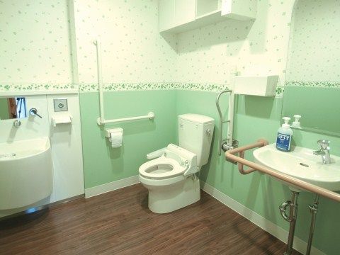 トイレは、淡いグリーンを基調とした内装で、清潔感がある。洗面台や便器の周囲には手すりがあり、個室内を安全に移動していただける。