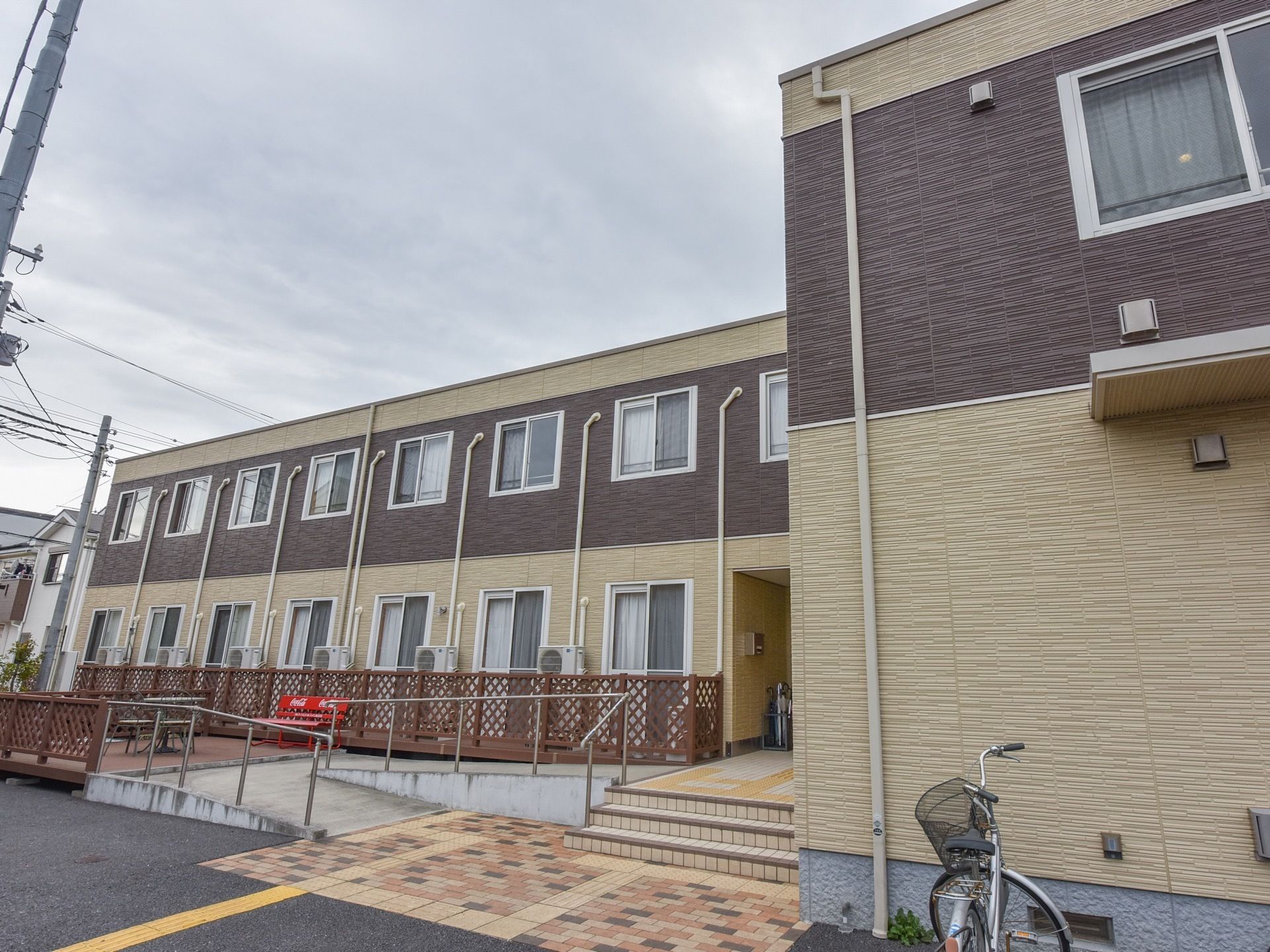 施設は二階建てである。階段と手すり付きのスロープがあり、スロープの先にはテーブルと椅子が並べられている。