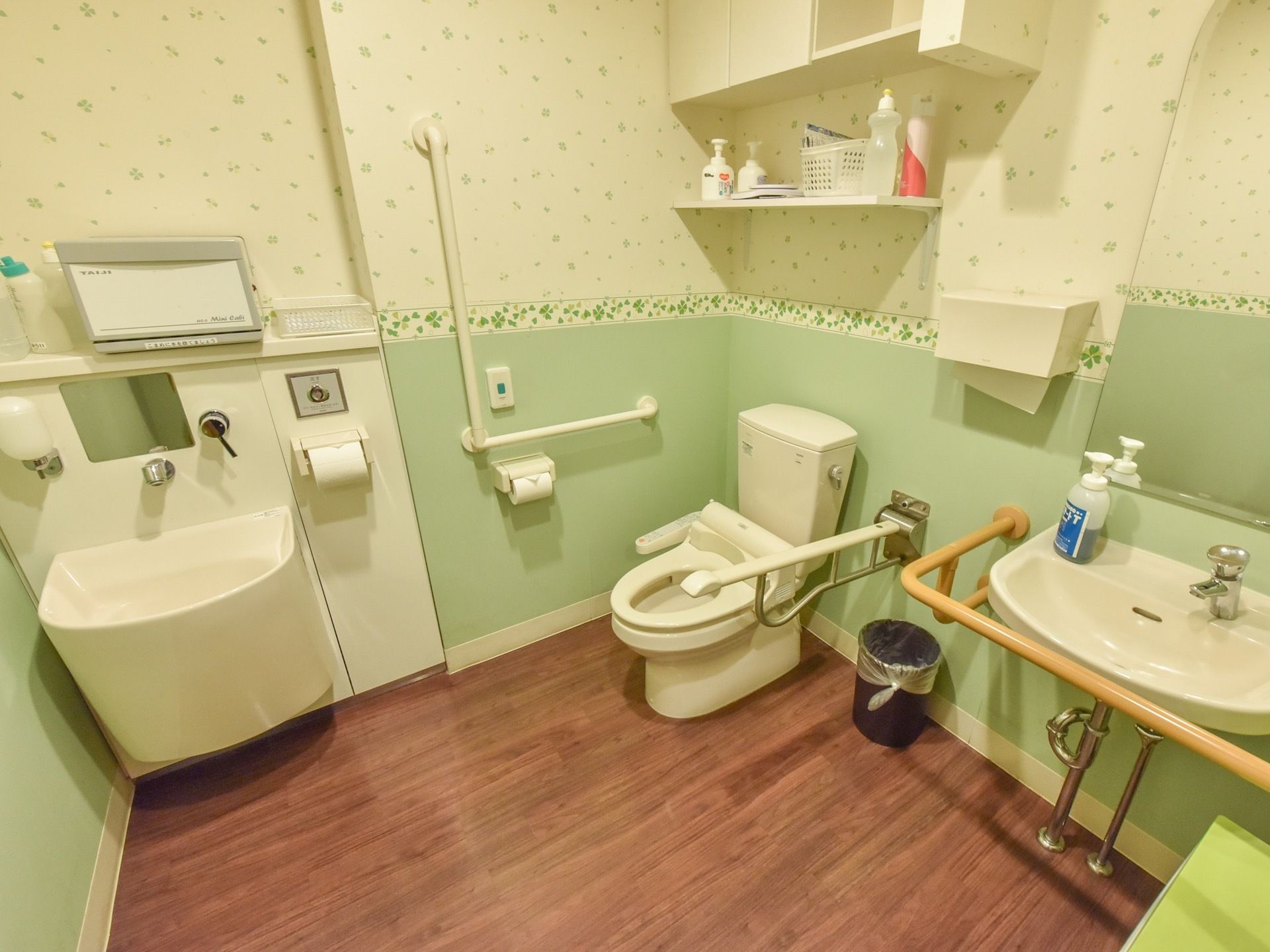 トイレには洋式便器が設置されている。便器の両側には手すりがある。壁には固定式、反対側には可動式のものが取付けられている。