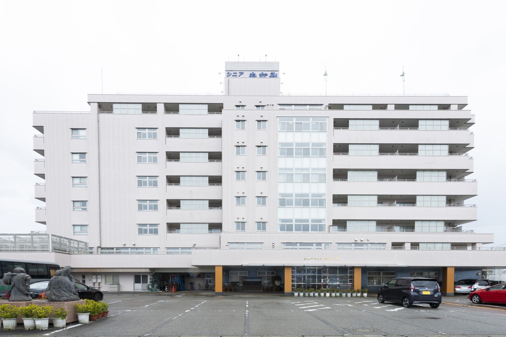 建物の１階部分には、屋根付きの広いスペースが設けられている。白や茶色の植木鉢に入った草木が、数多く並べて置いてある。