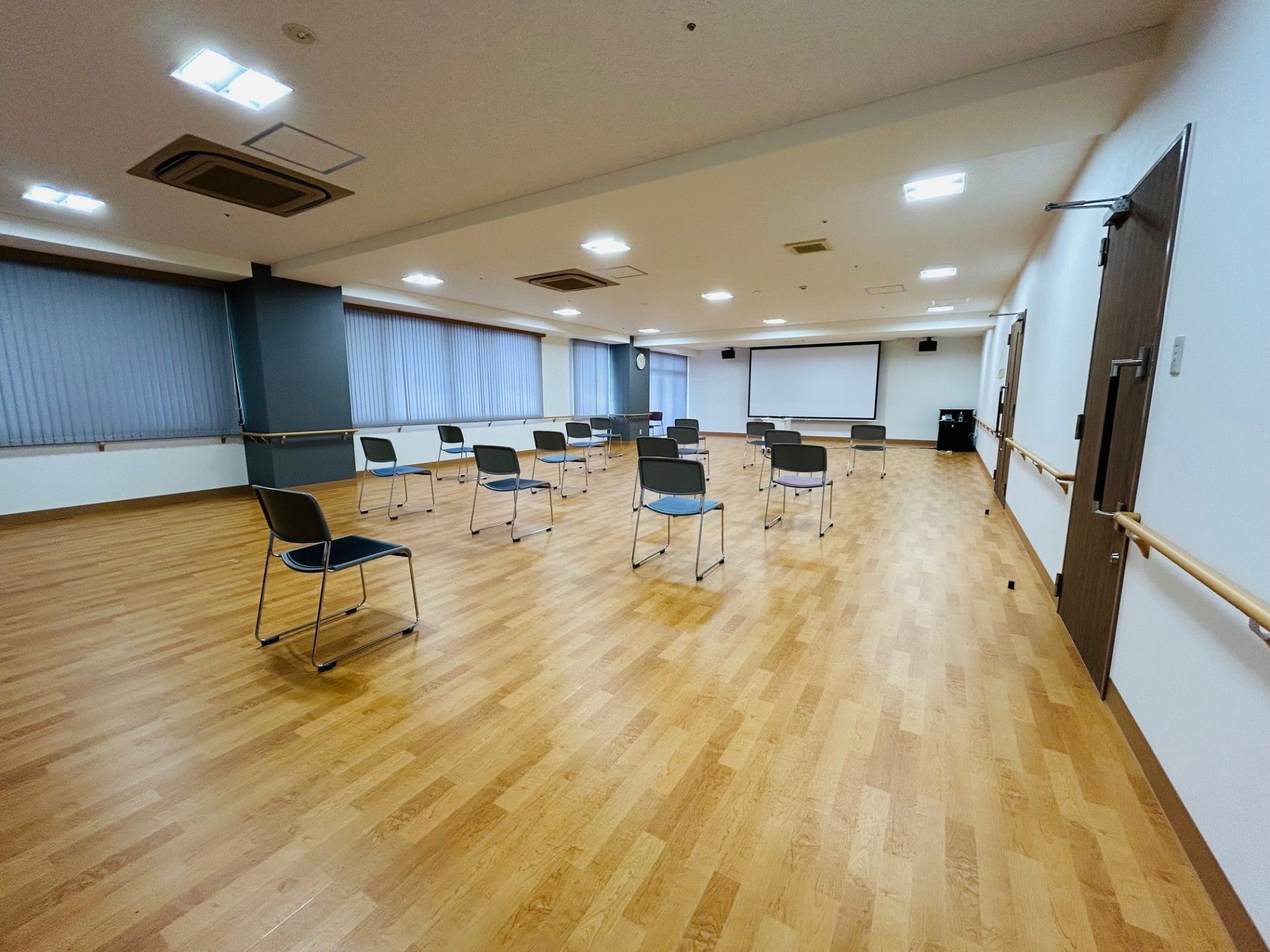 横幅のある広いステージが、集会場の正面に設置されている。ステージの右端には、なだらかなスロープと手すりが取り付けられている。