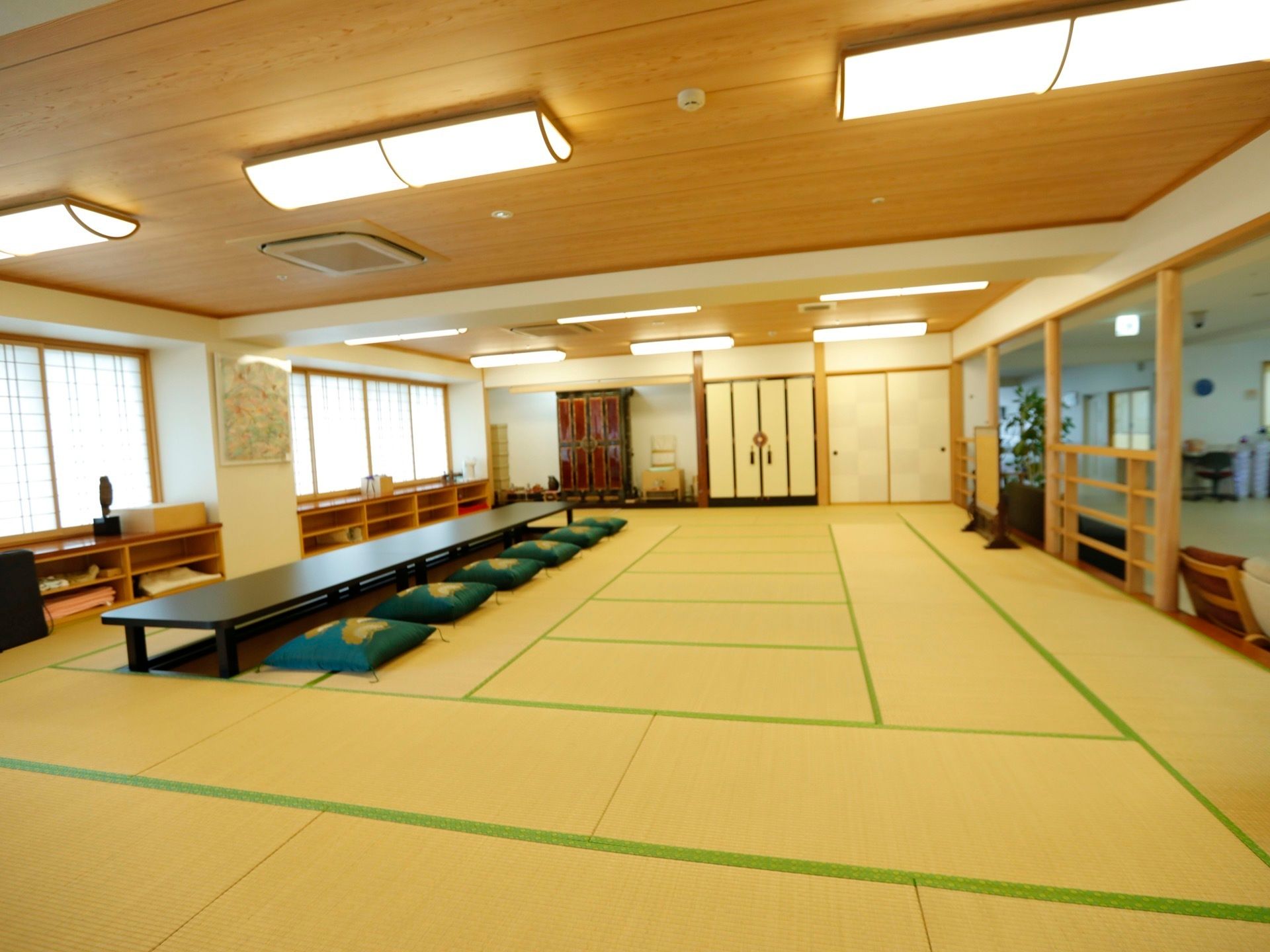 障子窓から穏やかな光が差し込む明るい娯楽室である。左端に、深緑色の座布団と長方形のテーブルが置いてある。