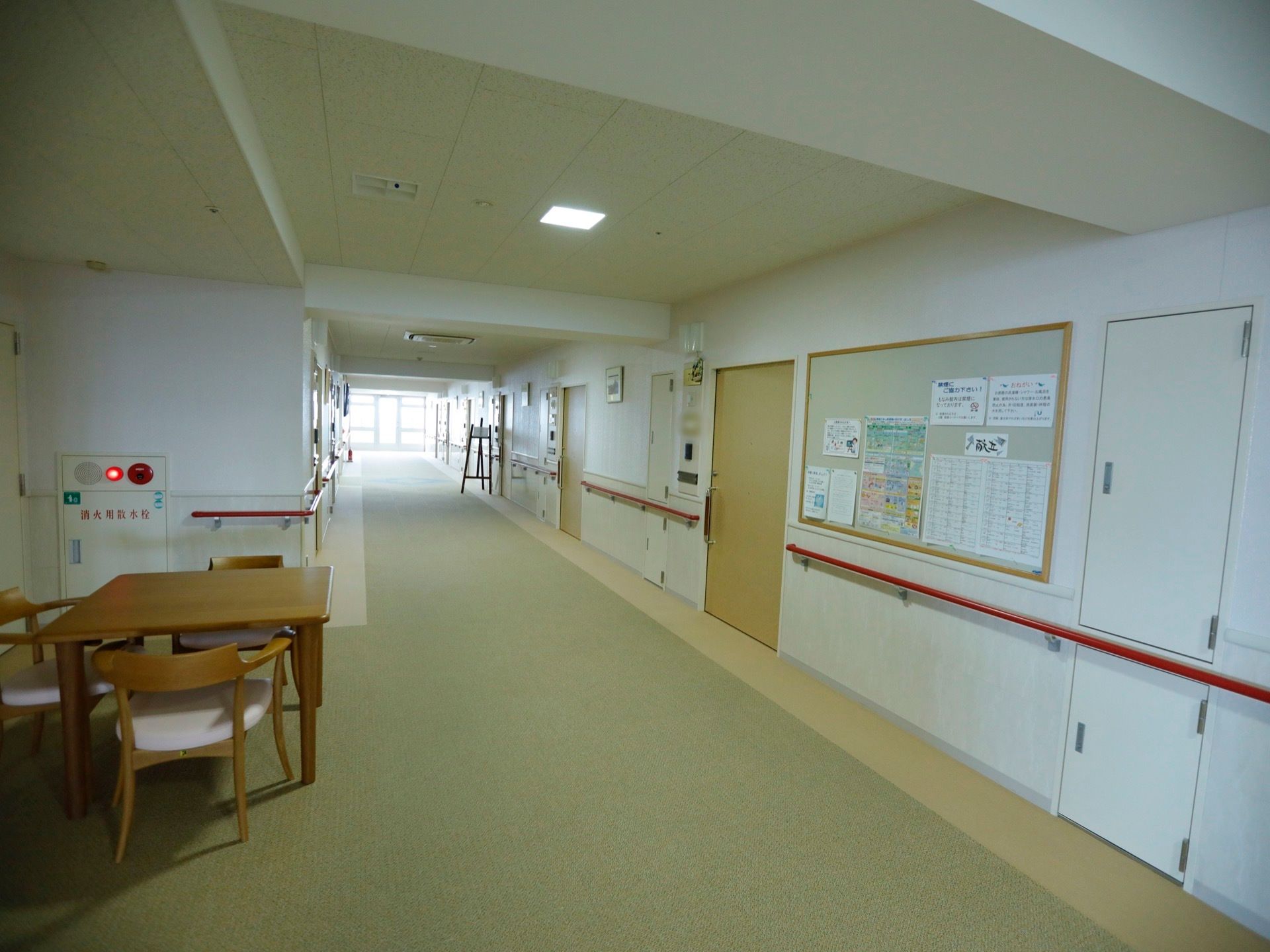 横幅のある広い通路は、ベージュ系の落ち着いたデザインである。右側の壁には掲示板があり、さまざまな書類が貼ってある。