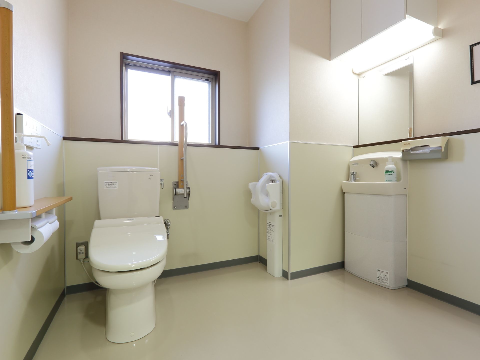 トイレルームには便座の横に手すりがあり、右手にはハンドソープが付いている洗面台があって電灯もついている。