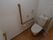 トイレはタンクの上に蛇口の付いているタイプになっており、壁には丸いタオル掛けや手すり、呼び出しボタンが備えてある。