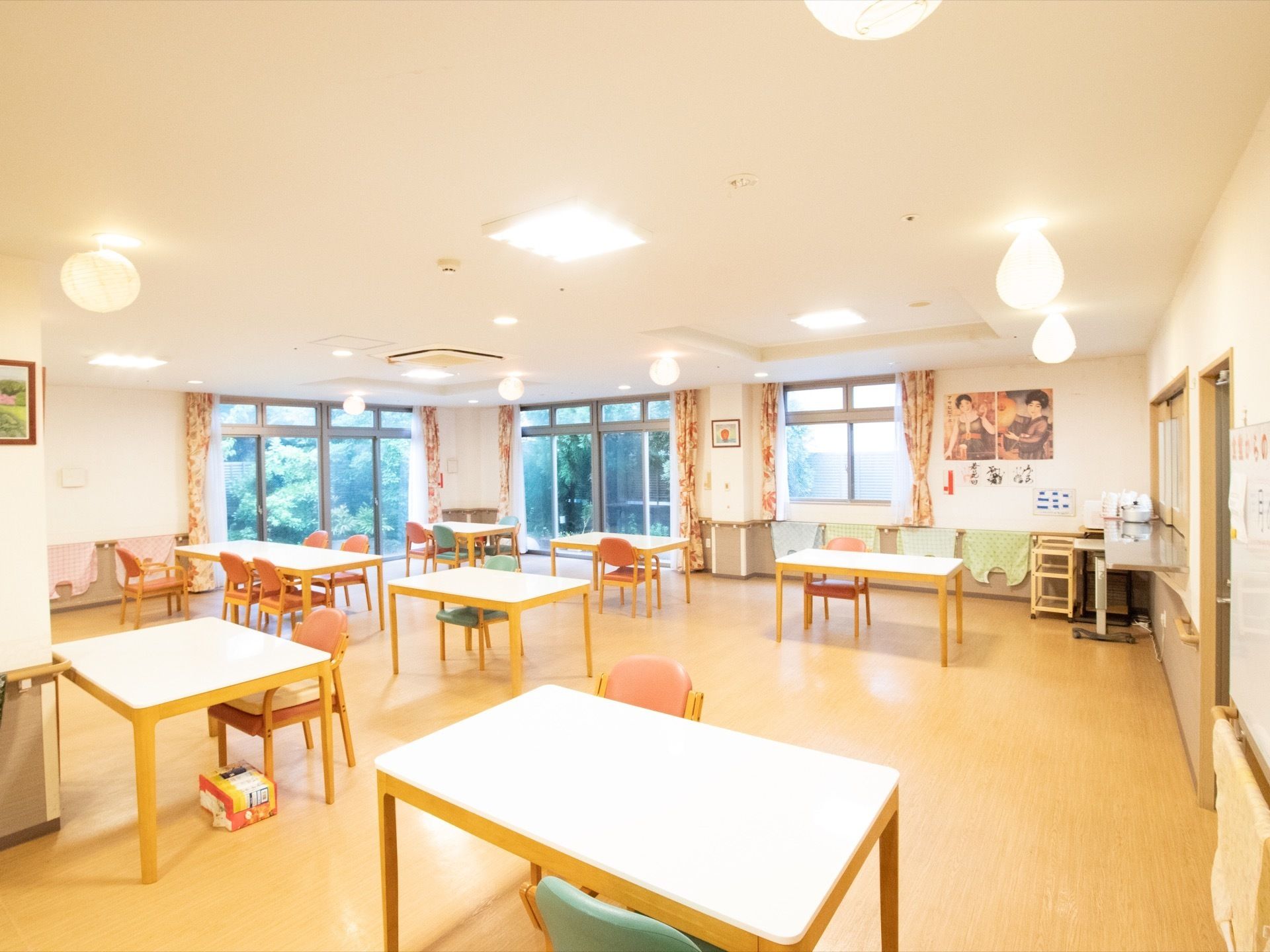 天板が白いテーブルと、ピンクやブルーの椅子が備えてある。壁にはポスターや絵などが飾られ、カウンターの側にはワゴンが置かれている。