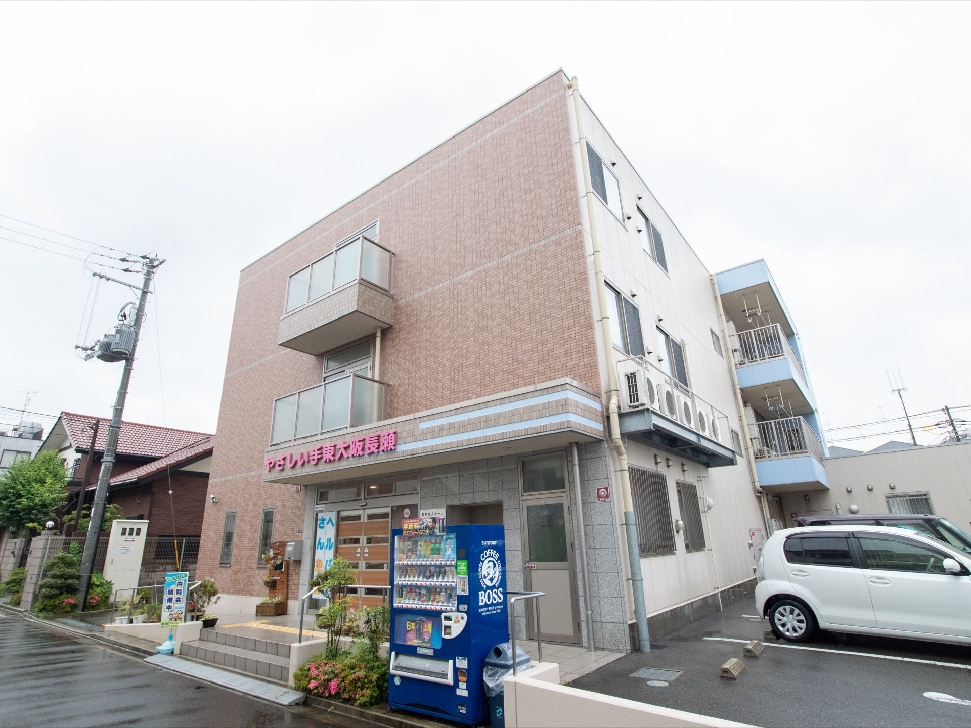 表の壁がレンガ調になった３階建てになっている。玄関の正面には階段が２段あり、両サイドは段差のないスロープになっている。