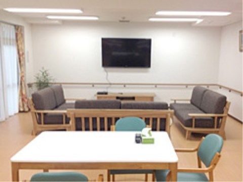 壁掛けテレビの手前に応接セットが置かれている共有スペース