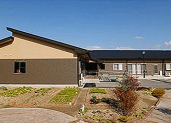 平屋建ての建物はブラウン系で日当たりのいい場所に建っている。ホームの前には菜園がある。