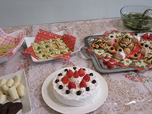 一口大に切られたバナナが盛られた皿やカナッペが並んだ皿、ショートケーキなどおやつがたくさん置かれている。