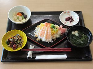 大きな海老がや錦糸卵が乗ったちらし寿司をメインとして煮物やあえ物、吸い物などが並べられている。