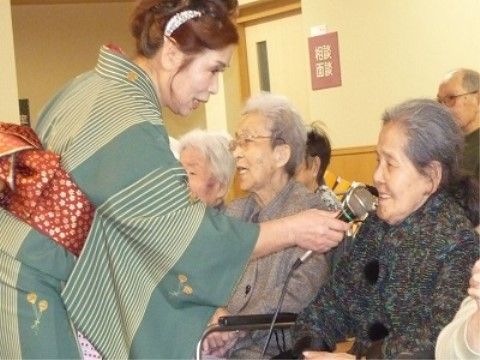 マイクを向けられ、少し照れながらも歌を楽しむ利用者様の様子