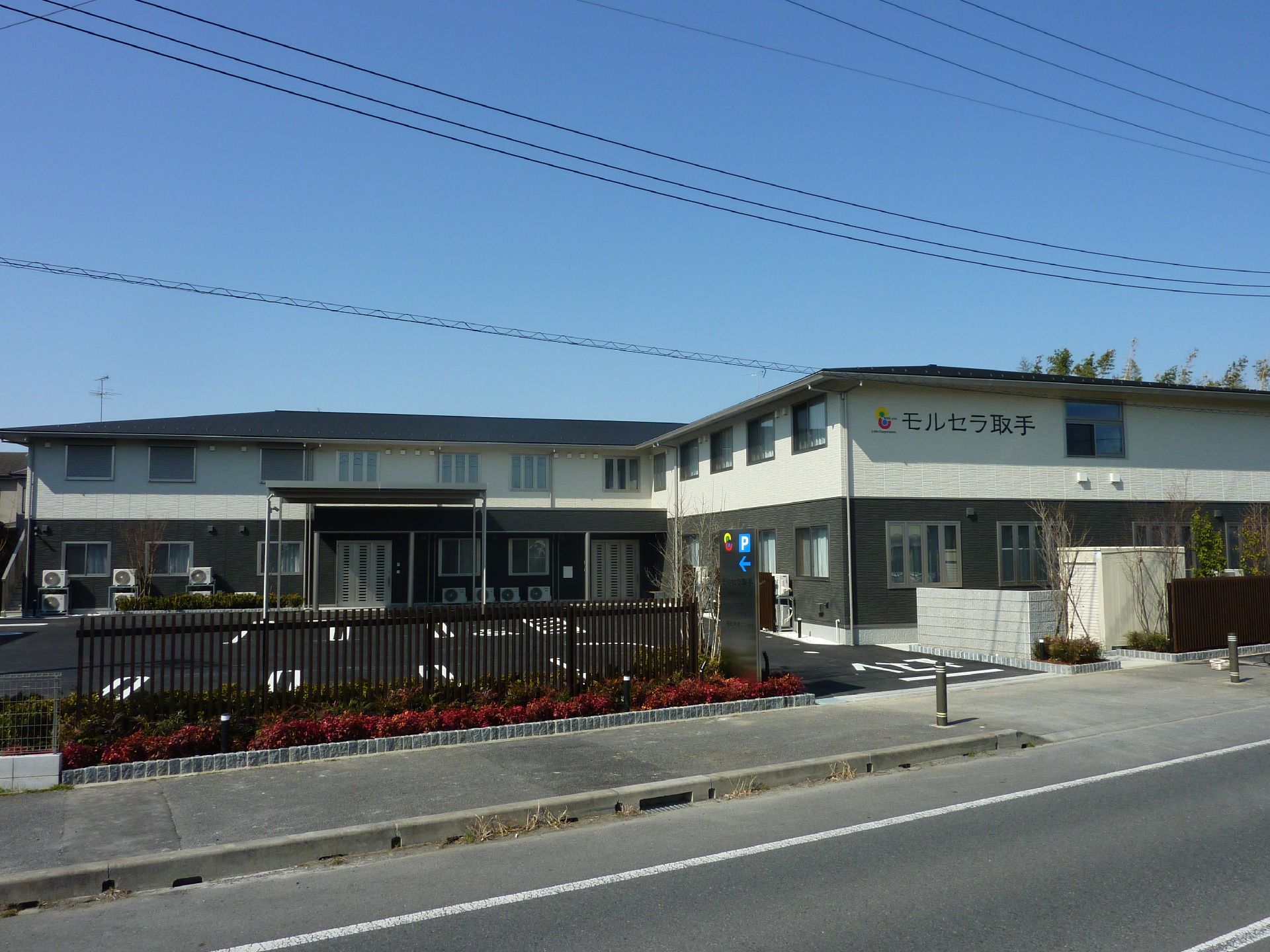 ストライプ柄のシャツを着た高齢男性が福祉車両から下りようとしていて若いスタッフが手伝っている。