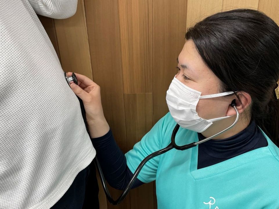 高齢者と一緒にカルテのようなものを眺めている施設内スタッフとの2ショット