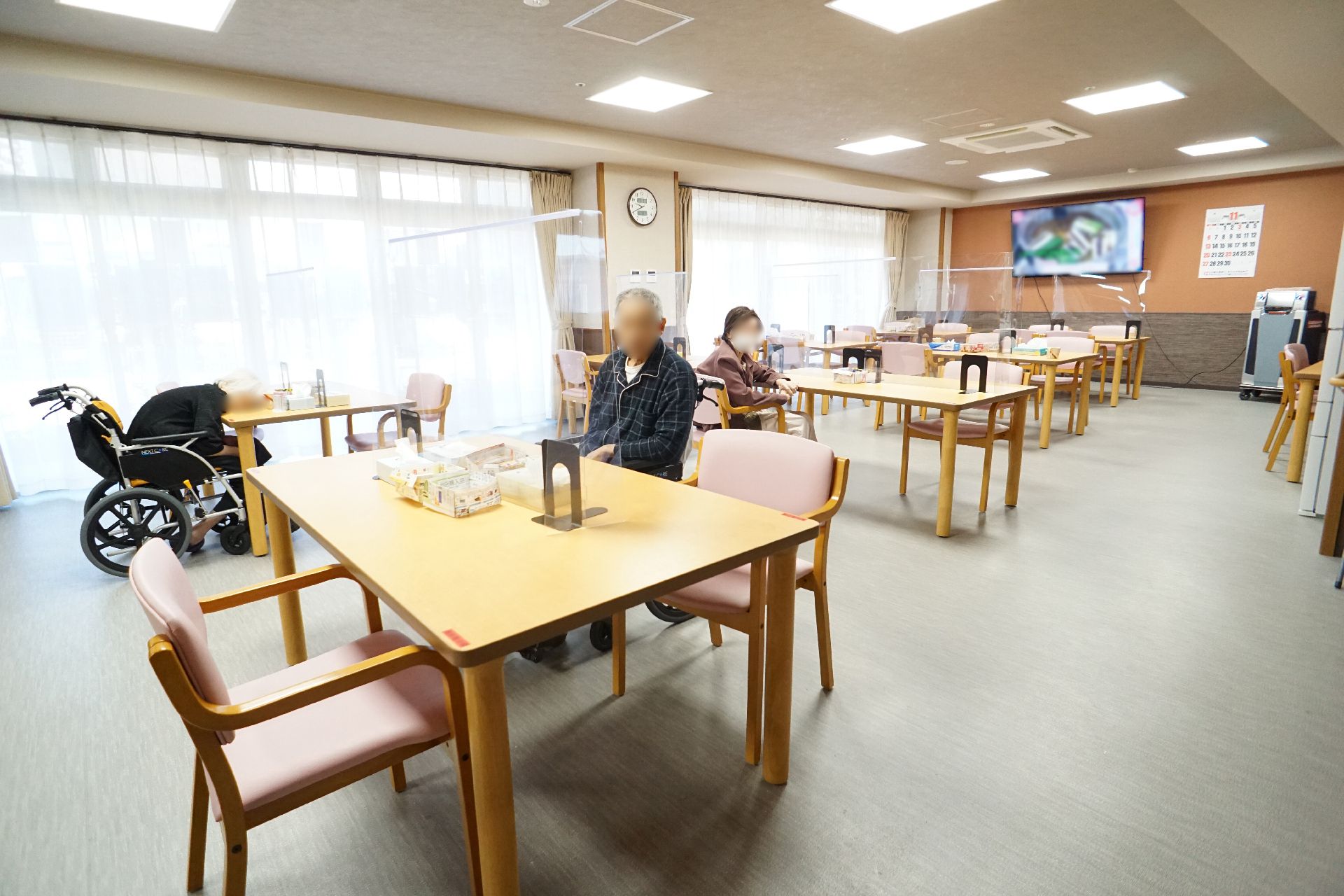 高齢者の方にタオルをかけてマッサージしているスタッフと振り返りながら会話する女性の様子