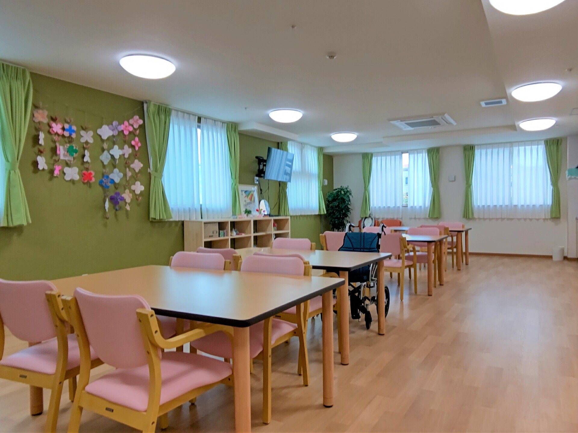 エプロンを付けた若い女性スタッフに手伝ってもらいながらフラワーアレンジメントを楽しんでいる高齢男性。