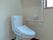 温水便座が設置されたトイレは広く、トイレットペーパーホルダーやエル字型の手すりが付いている。