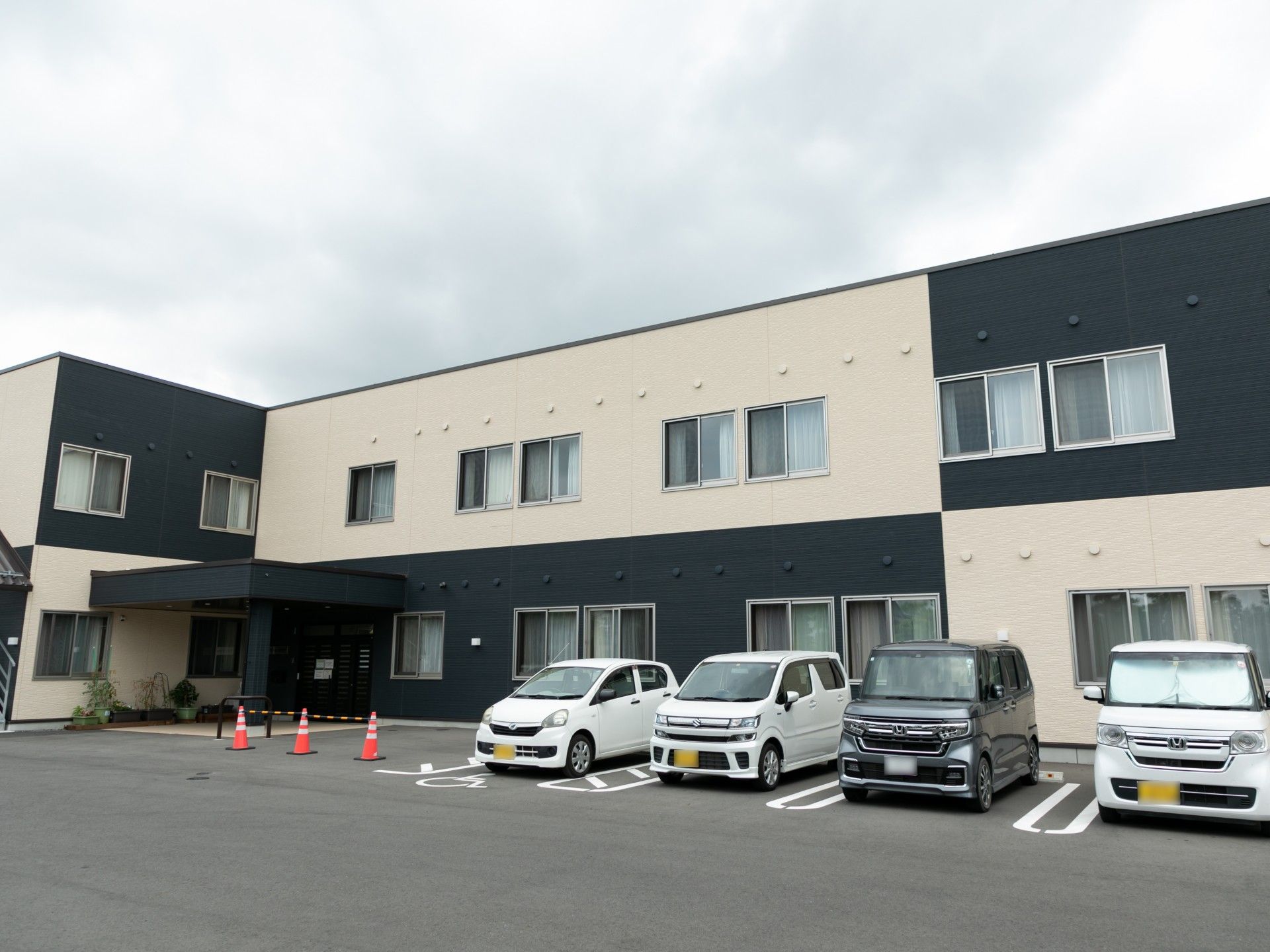 ボーダー柄のエプロンを付けた女性スタッフが白いシャツを着た高齢男性の介助に当たっている。