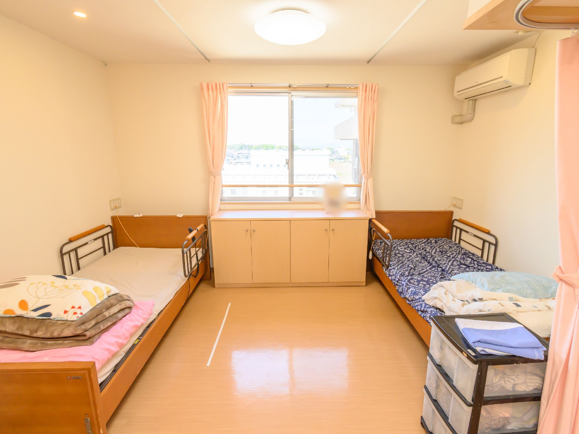 窓から光が入り、介護ベッドや収納が置かれている居室