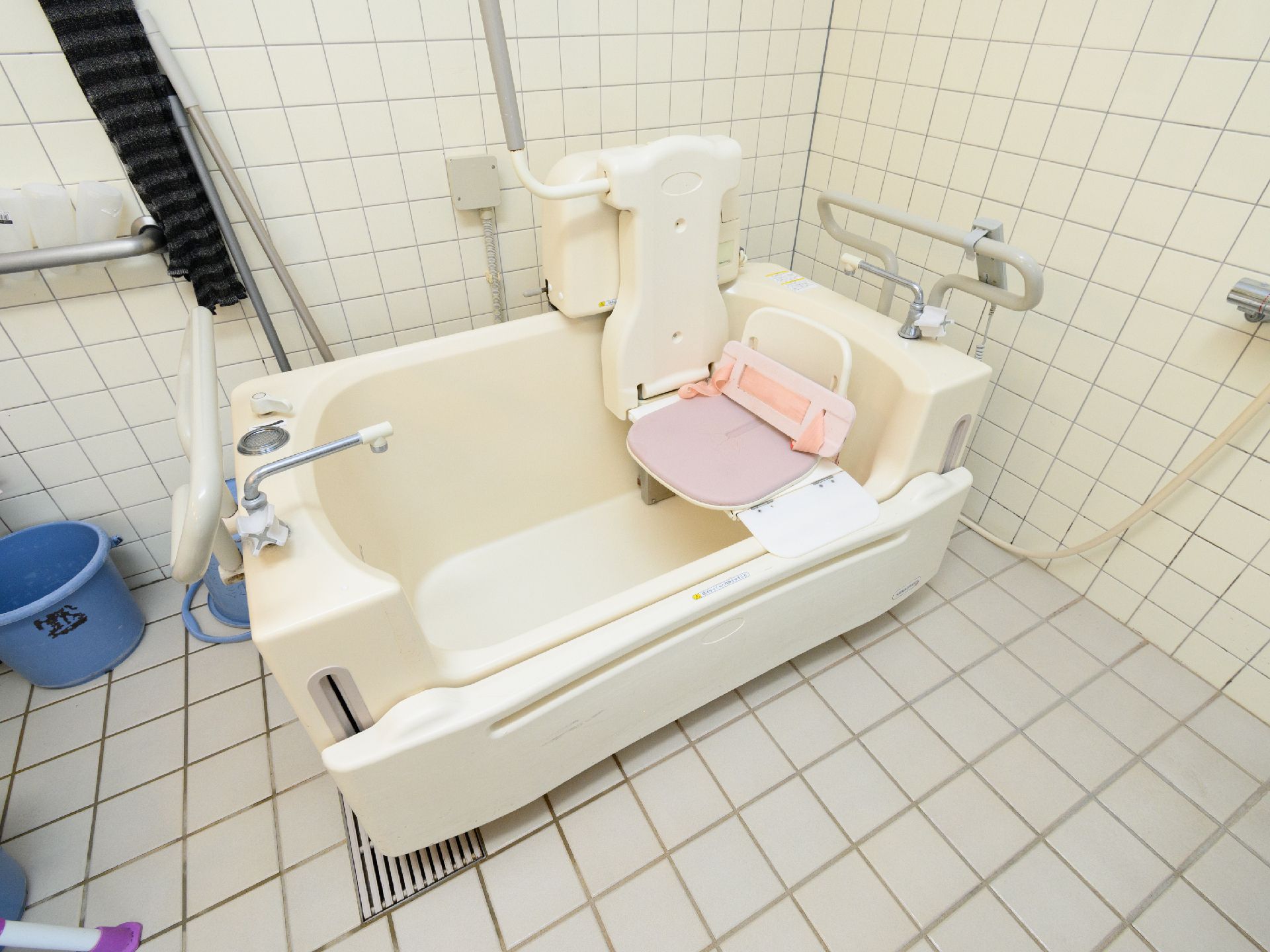 高齢者の方にタオルをかけてマッサージしているスタッフと振り返りながら会話する女性の様子