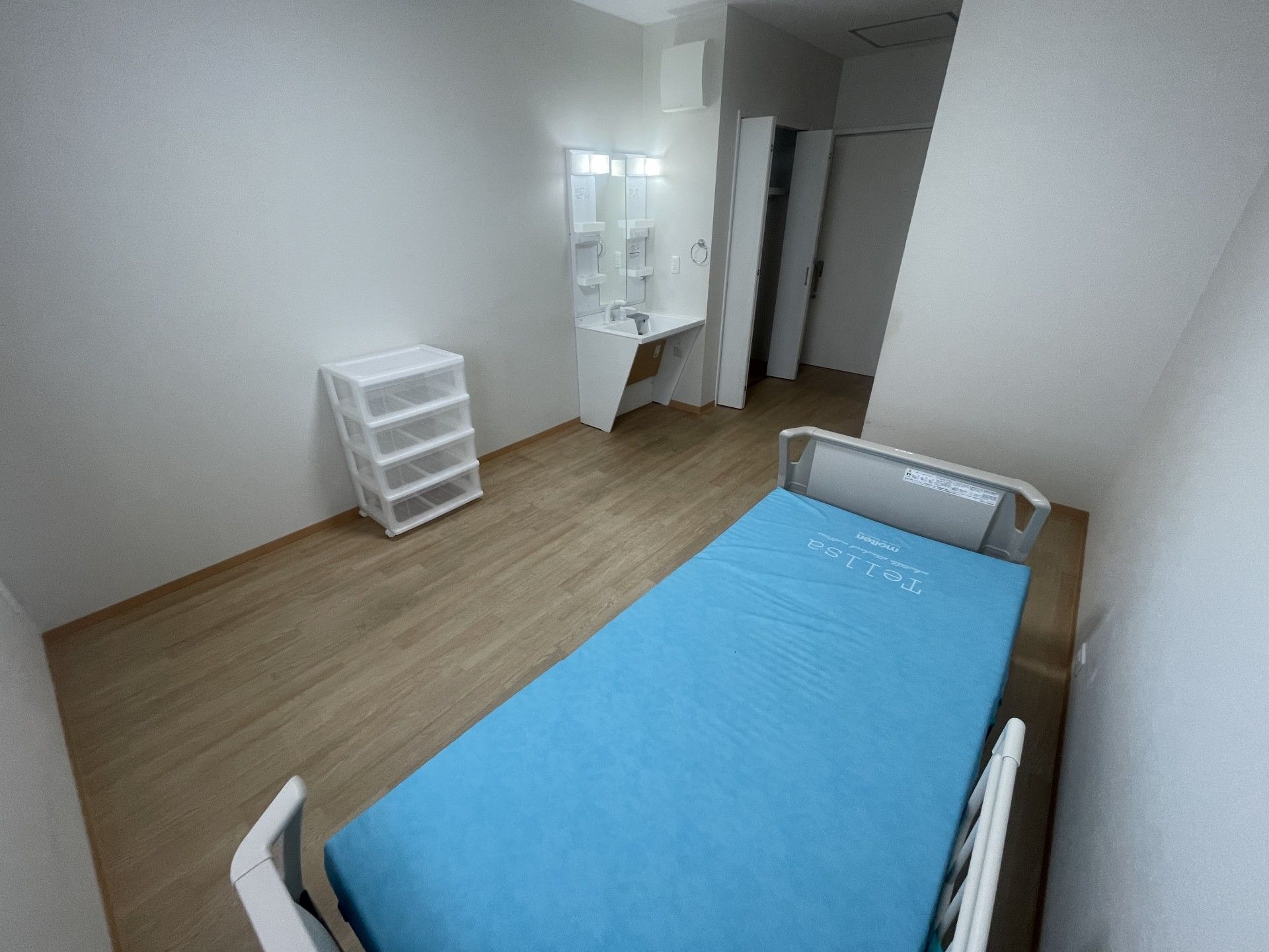 白いポロシャツを着た女性スタッフと車いすの高齢女性が笑顔で話している。