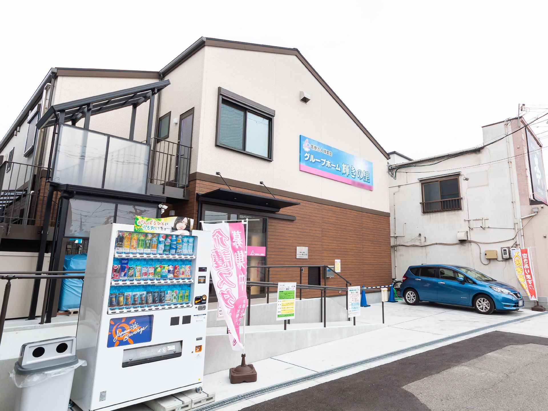 自動販売機が目の前にある車の止まった２階建ての建物