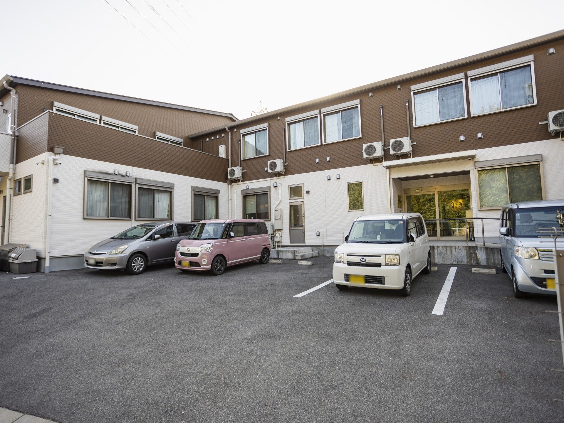 こちらを向いて笑顔になる車いすの高齢女性と介護施設の女性スタッフの様子