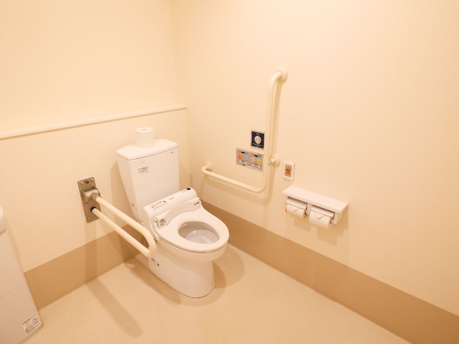 部屋の隅に配置された手すりに囲まれているトイレ