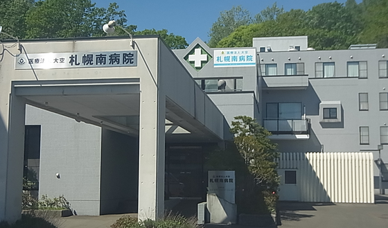 誰かに向かって手を振っている車いすの高齢女性のそばに寄り添い、笑顔でサポートしている女性スタッフ。