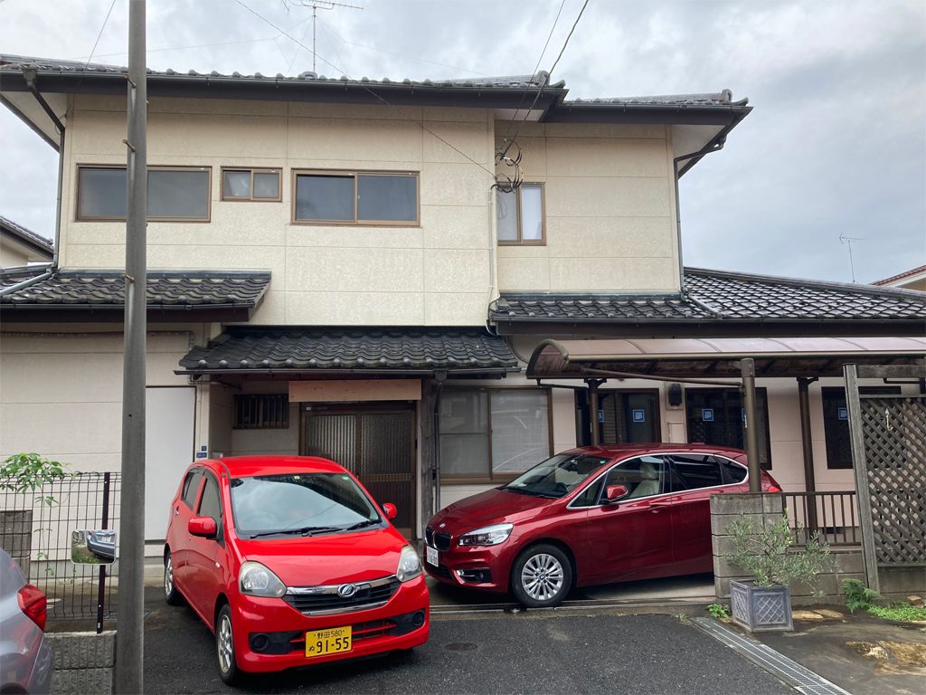 車が家の前に止められている。一般の民家と同じような外観で瓦屋根が付いている。