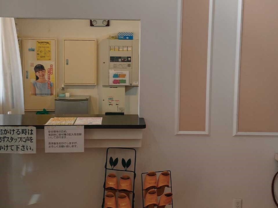 受付には名前を書き込む帳簿があり、スリッパラックも置かれている。カウンター内にはポスターなどが貼られている。