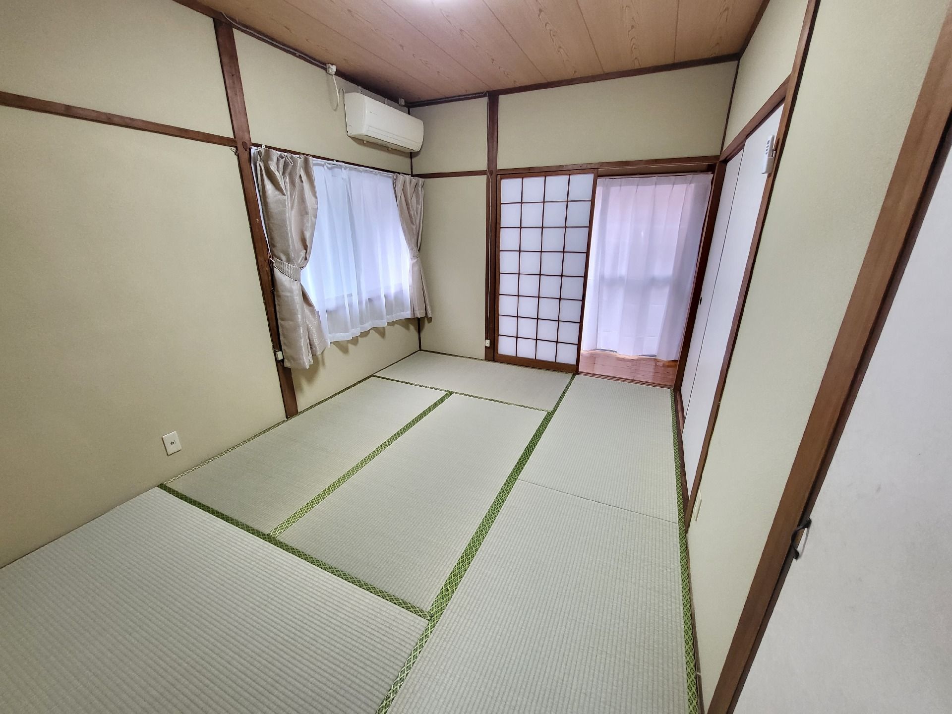 ピンクのエプロンを付けた若い女性スタッフが車いすの高齢女性のそばにいて、二人は笑顔で話している。