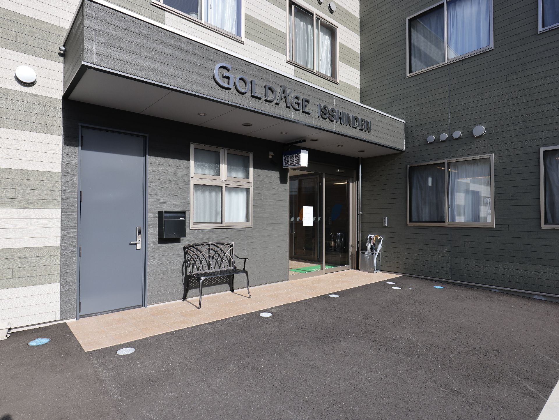 広い駐車場が付いた２階建ての建物は日当たり良好でコの字型。敷地内には車が止まっている。