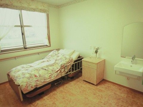 入居者様用の居室はゆったりとした広さがあり、窓際には柵の取りつけられたシングルベッドが設置されている。