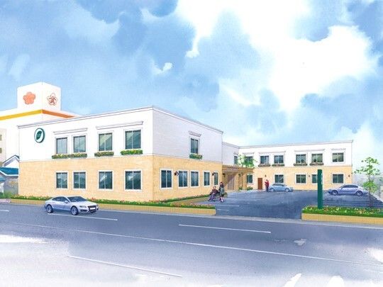 広い駐車場が付いた２階建ての建物は日当たり良好でベージュと白の外壁。道路に面している。