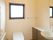 窓が付いたトイレは広く、手すりや手洗い場も設置され、明るい雰囲気。