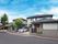 グレーの屋根が付いた２階建ての建物は一般の住宅のような外観。敷地内の駐車場には車が止まっている。