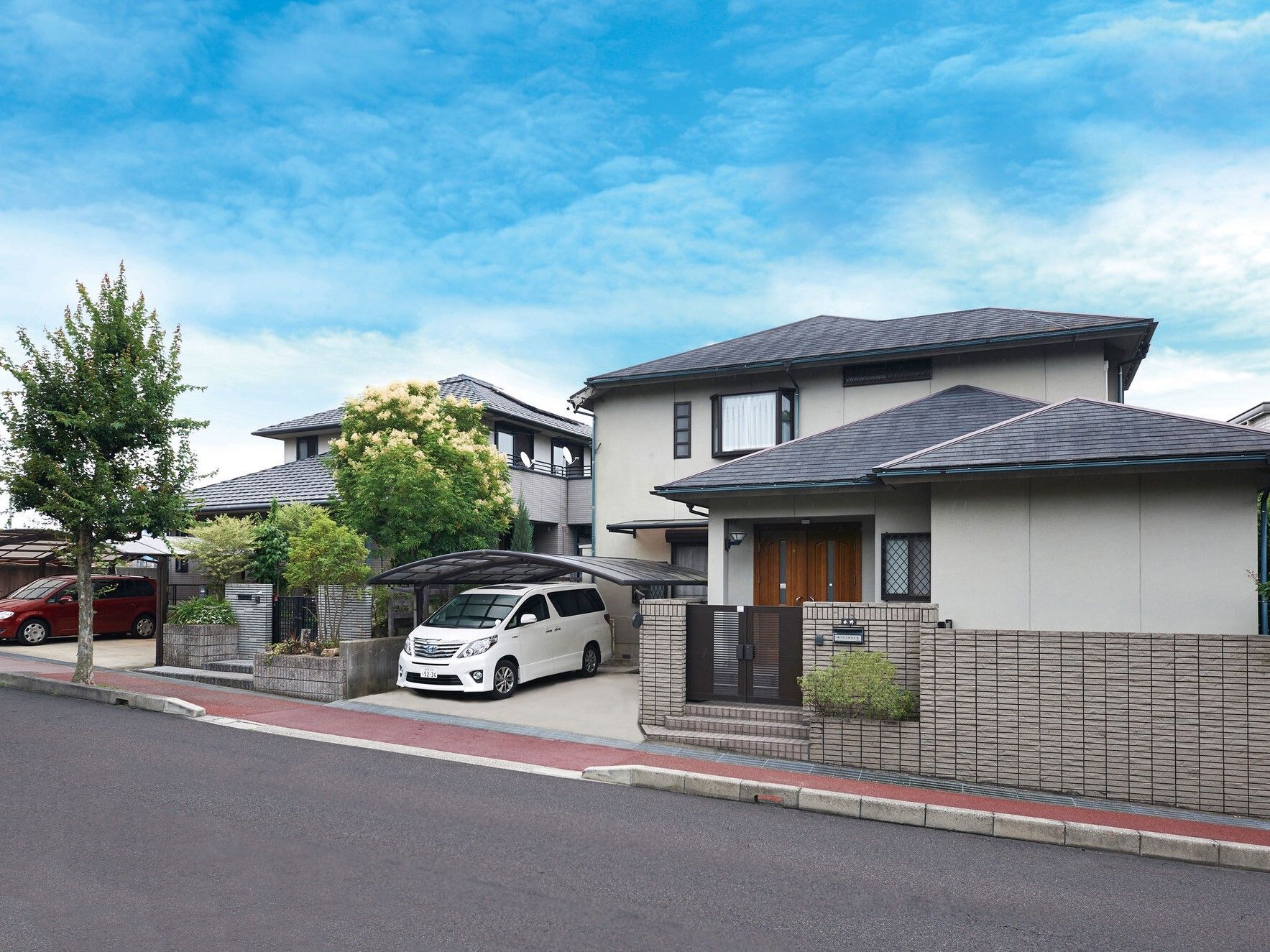 車を泊まっている駐車場が付いた一般の住宅と変わらない２階建ての建物。