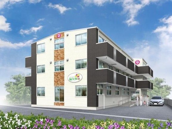 各フロアにベランダがあり、敷地内には駐車場もある3階建ての建物。玄関には手すり付きのスロープが付いている。