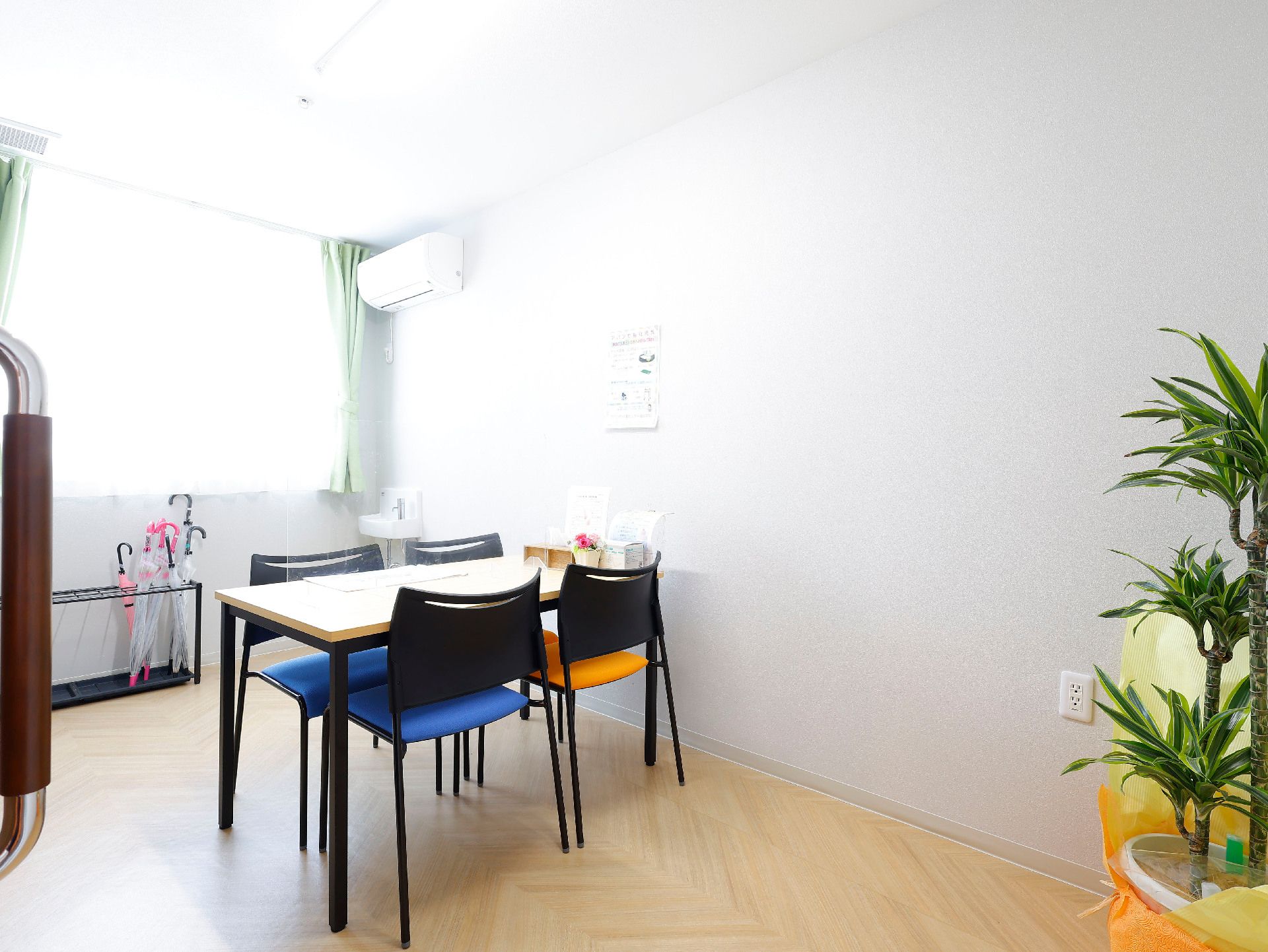 白い壁の部屋に置かれた木製の机とカラフルなクッションが付いた椅子