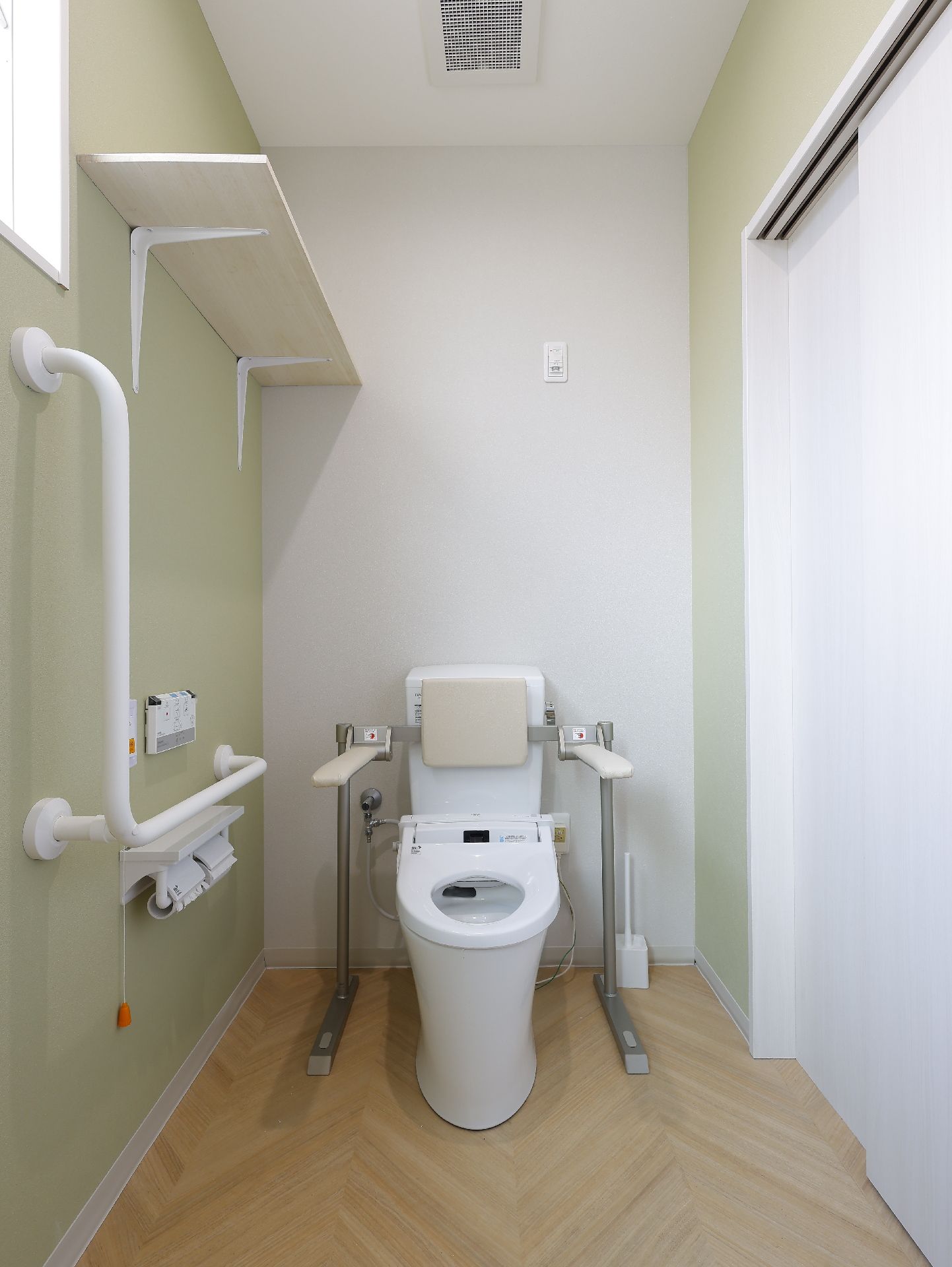 白い手すりに囲まれた洋式便器が置かれている白い壁の部屋