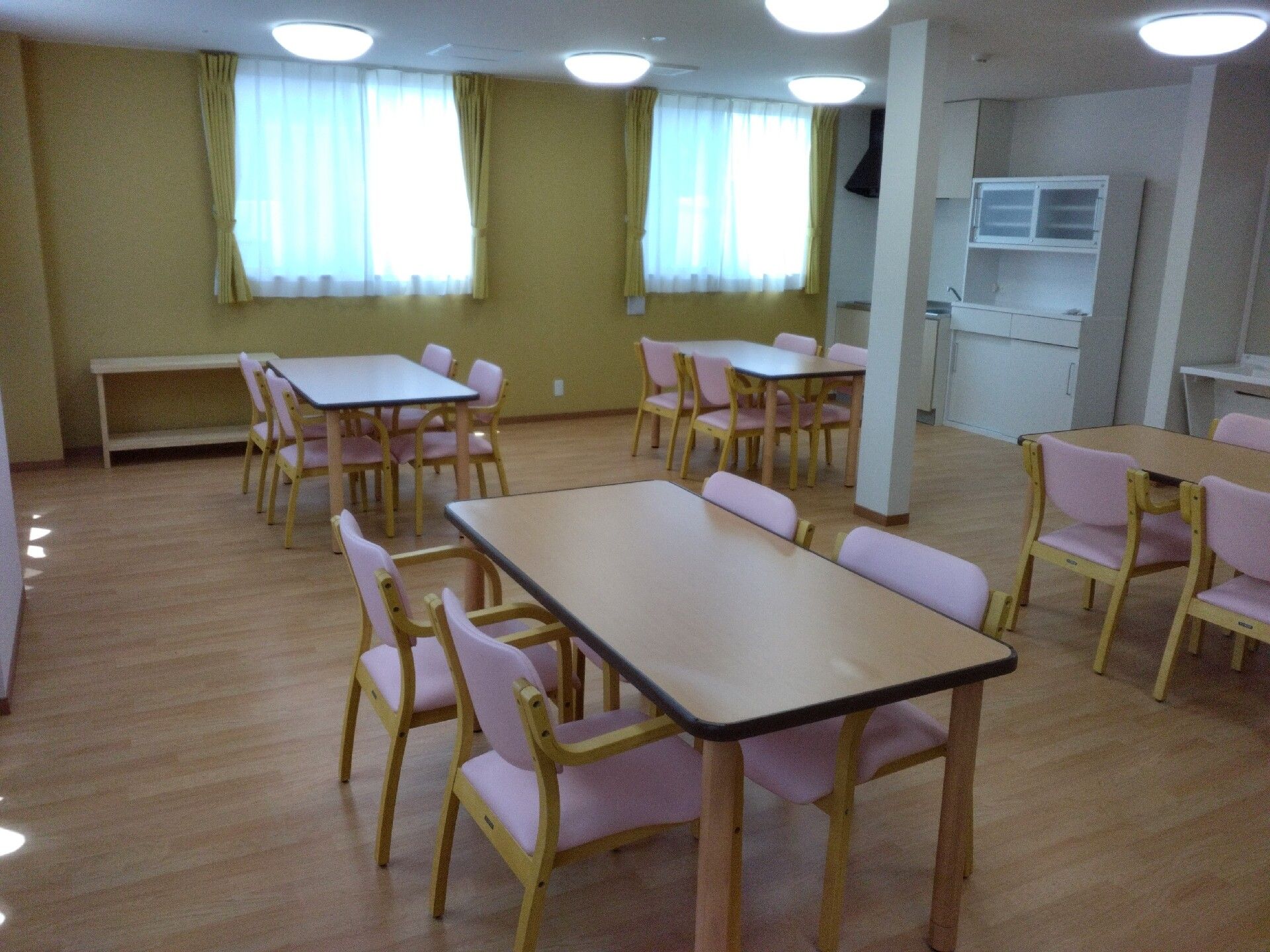 立ち入上がりろうとしている車いすの女性を補助するスタッフの表情。笑顔で対応している様子